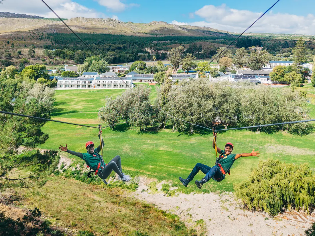 Two riders racing side by side on the dual zipline at Houw Hoek Zipline